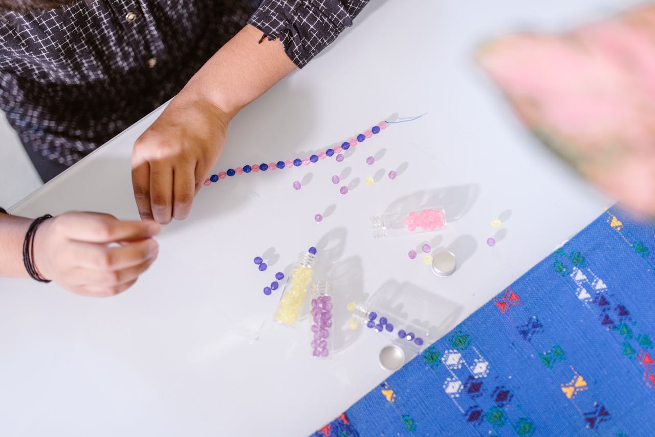 A person creating a beaded bracelet indoors, showcasing creativity and craft skills.